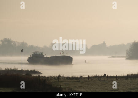 Schiff auf dem Fluss IJssel in der Nähe von Wilsum während eines frühen sonnig und misty morning. Stockfoto