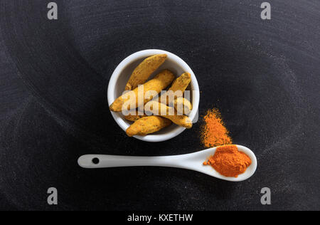 Gelbwurz aus Porzellan Schüssel und Löffel, schwarzer Hintergrund Stockfoto