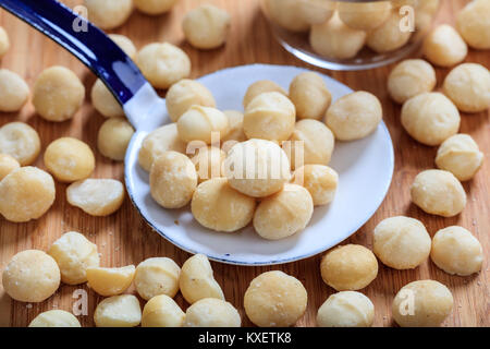Macadamia Nüsse und eine alte Pfanne auf einem Tisch Stockfoto
