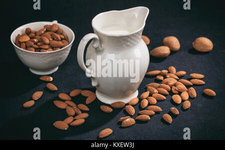 Vegane Milch aus Mandeln auf schwarzem Hintergrund Stockfoto