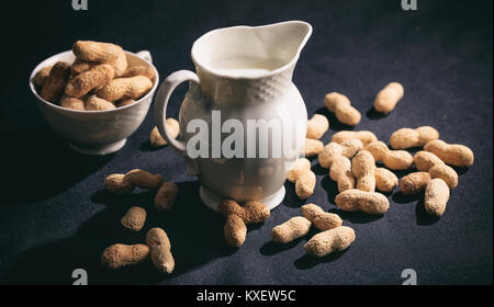 Vegan Milch aus Erdnüssen auf schwarzem Hintergrund Stockfoto