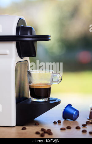 Und Espresso. Espressomaschine auf einem Holztisch. Verschwommen grünen Hintergrund, Vorderansicht Stockfoto