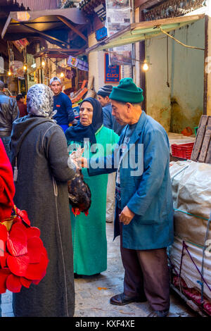 FEZ, Marokko - Dezember 10: Mann vorbei lebendig Huhn zu den Frauen auf der Straße Basar in Medina von Fez. Dezember 2016 Stockfoto