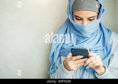 Muslimische junge Frau Verwendung von Smart Phone im Cafe Stockfoto