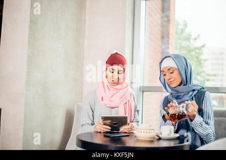 Weibliche muslimische Studenten mit Tablet-PC im Cafe Stockfoto