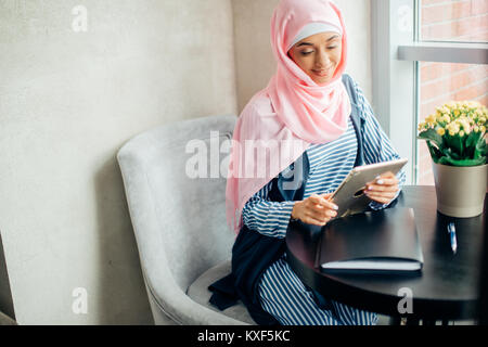 Weibliche muslimische Studenten mit Tablet-PC im Cafe Stockfoto