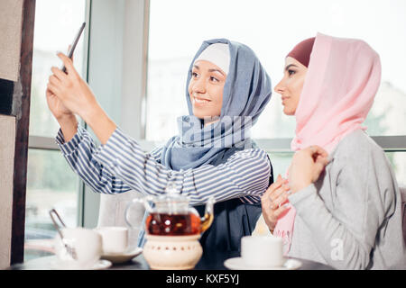 Zwei glückliche junge muslimische Frau, Selbstportrait mit Handphone im Cafe Stockfoto