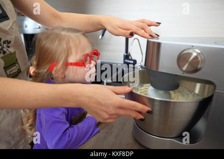 Mutter lehrt Tochter Torte zu kochen. Kochen mit Kind. Stockfoto