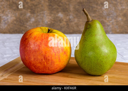 Noch immer leben in einen Apfel und eine Birne auf einer hölzernen Schneidebrett. Stockfoto
