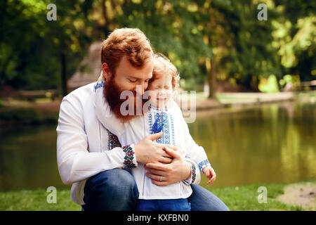 Rot - Heared Vater und rot-Heared Sohn Spaß haben in einem Park in einer traditionellen weißen Hemden mit Ornament Stockfoto