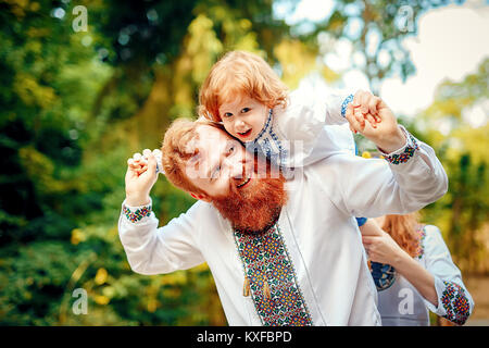 Rot - Heared Vater und rot-Heared Sohn Spaß haben in einem Park in einer traditionellen weißen Hemden mit Ornament Stockfoto