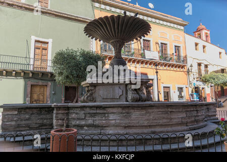 Die dekorative Stein Brunnen auf dem Plaza del Baratillo, an einem sonnigen Tag mit einem klaren blauen Himmel und farbenfrohe Gebäude im Hintergrund, in Guanajuato Stockfoto