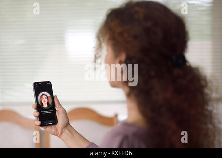 Frau mit Apple iPhone X in ihrer Hand einrichten Face ID, biometrische Authentifizierung, durch ihr Gesicht Scannen mit einer neuen Tiefe sensing Kamera aus verschiedenen Stockfoto