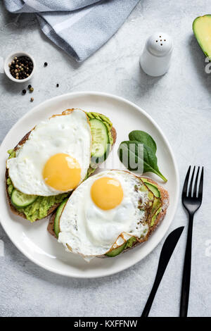 Spiegelei, Avocado und Gurke auf Vollkorn Toast. Gesundes Essen, gesundes Frühstück essen Konzept Stockfoto
