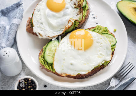 Gesundes Frühstück Toast mit Spiegelei, Avocado und Gurke auf weiße Platte. Detailansicht. Konzept der gesunden Ernährung, gesunder Lebensstil und Diät Stockfoto