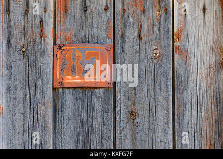 Rusty Grunge metal house Plakette Nr. 87 auf eine alte hölzerne Tür, vintage Zeichen in Griechenland. Stockfoto