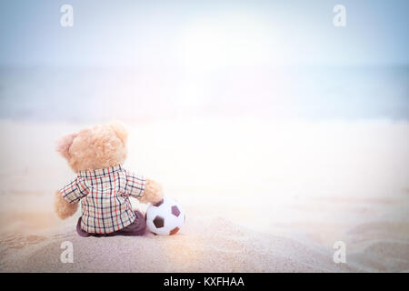 Teddy mit einem Fußball am Meer mit Kopie Raum zu schreiben und selektiven Fokus Punkt. Stockfoto