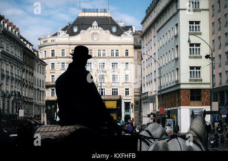 Pferdekutsche Fiaker mit Silhouette der Kutscher als Reiseleiter zu Fuß entlang der alten Straßen von Wien, Österreich Stockfoto