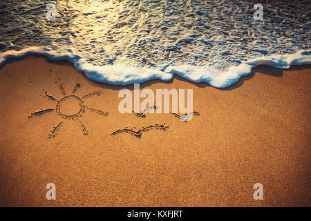 Closeup Wellen, Sonne und Palm Zeichnung auf dem Sandstrand in der Nähe des Meeres. Stockfoto