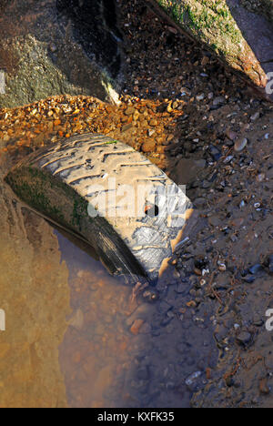 Auf einem Strand in Norfolk, England, Vereinigtes Königreich, eine alte ausrangierte Reifen halb begraben. Stockfoto