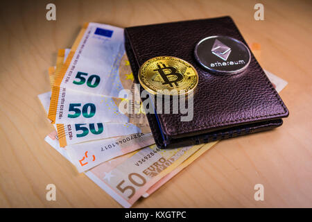 Finanzkonzept mit physischen Bitcoin und des Astraleums über eine Brieftasche mit Euro Rechnungen Stockfoto