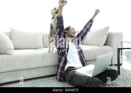 Happy Guy frohlockt mit seinem Hund sitzt in der Nähe der Couch im Wohnzimmer. Stockfoto