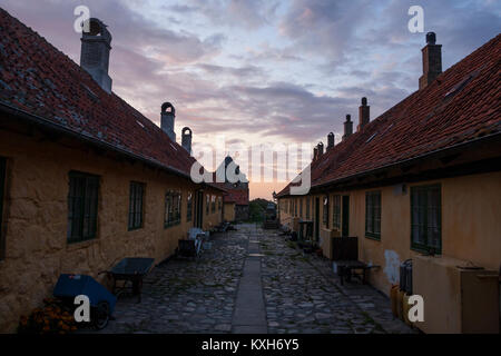 Gelbe Wohnbauten und die Straße (Gaden) nach Sonnenuntergang auf Frederiksø, Ertholmene, Bornholm, Dänemark Stockfoto