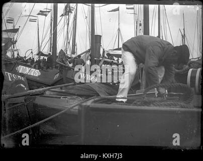 1904 Amsterdam Niederlande - ein Fischer strafft Seile auf sein Schiff während der 1904'Vlootdagen' ('Flotte Tagen') in Amsterdam, eine jährliche Veranstaltung, die von der niederländischen Royal Marine gehostet auf die Anleihe es mit Amsterdam ist zu betonen, zurück gehen, so weit wie 1655, initiiert von Admiral Michiel De Ruyter. Stockfoto
