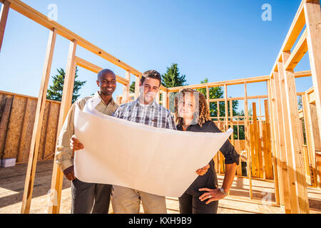 Ein paar Bewertungen Pläne für ein Haus mit ihrem Auftragnehmer/Architekt auf der Baustelle. Stockfoto