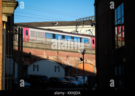 Eine CrossCounty Zug passiert über Geschäfte und Gebäude auf ein Rail Track im Zentrum der Stadt Leeds, Yorkshire, Großbritannien Stockfoto