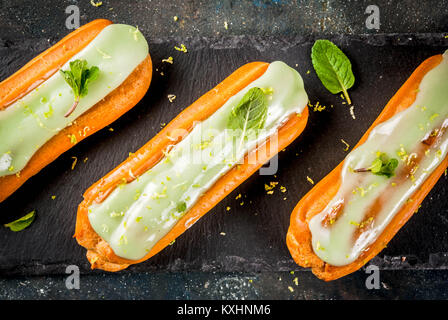 Traditionelle französische Dessert. Mojito Eclairs mit Limettenschale und Minze, auf dunkelblauem Hintergrund, kopieren Sie Raum, Ansicht von oben Stockfoto