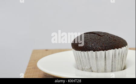Chocolate Muffin in Papierfach auf Holzbrett Stockfoto