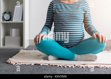 Schwangeren Yoga Übung zu Hause. Schwangerschaft Yoga und drinnen Fitness Concept. Unbenotete kontrastarmen Aufnahmen mit natürlichen Fenster Licht. Stockfoto