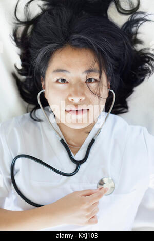 Hochwinkelporträt einer Ärztin, die mit Stethoskop dem Selbstherz zuhört Stockfoto