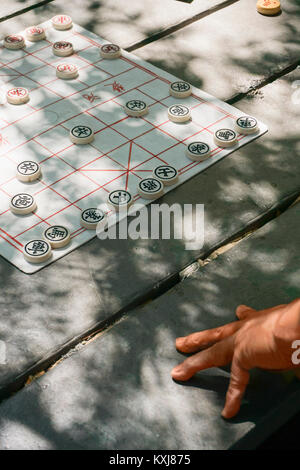 Zugeschnittenes Bild einer Person mit chinesischem Schach auf dem Tisch Stockfoto