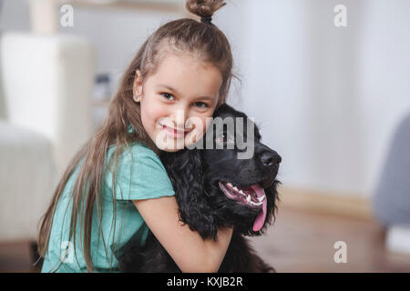 Porträt eines lächelnden Mädchens, das Cocker Spaniel zu Hause umarmt Stockfoto