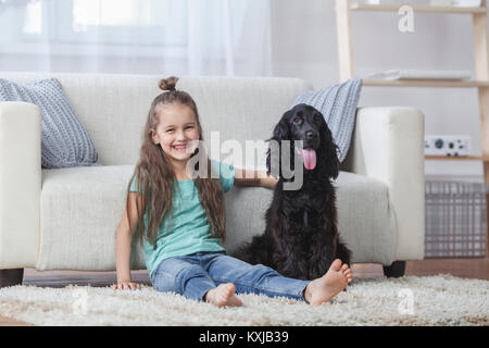 Portrait of cute girl sitting by Cocker Spaniel on rug at Home Stockfoto