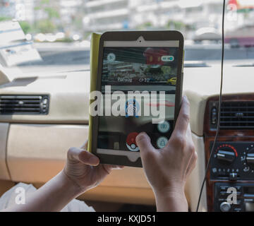 Bangkok, Thailand - 7 August 2016: Hand Apple Ipad Mini 2 Tablette die Pokemon Gehen, das am Bildschirm im Auto auf dem Weg Foto b Stockfoto