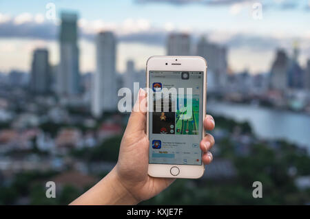 Bangkok, Thailand - 7 August 2016: Hand mit Apple iPhone 5 Handy die Pokemon Gehen, das am Bildschirm über das Bangkok Stadtbild phot Stockfoto