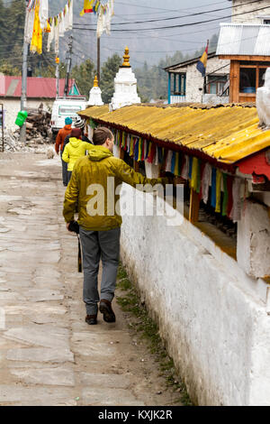 Mountain Village Chame, Annapurna, Nepal. Touristen zu Fuß rund um den Stupa und tibetische Gebetsmühlen drehen. Stockfoto