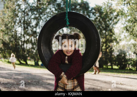 Junge Mädchen spielen auf Reifen Schwingen Stockfoto