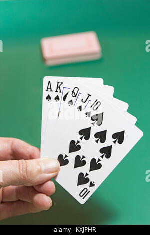 Hand mit einem Royal Flush hand mit Defokussierten Satz Karten auf einem grünen Hintergrund. Stockfoto