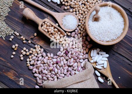 Verschiedene ungekochtem Getreide auf dem Holztisch in der Schüssel und textile Tasche von oben. Stockfoto