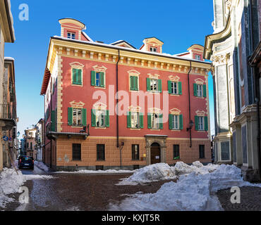 Typischen bunten Gebäude auf engen, kopfsteingepflasterten Straße mit Schnee in der Stadt von Cuneo in Piemont, Norditalien. Stockfoto