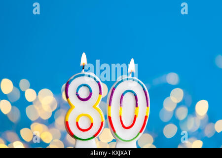 Nummer 80 Geburtstag Kerze gegen einen hellen Lichtern und blauer Hintergrund Stockfoto