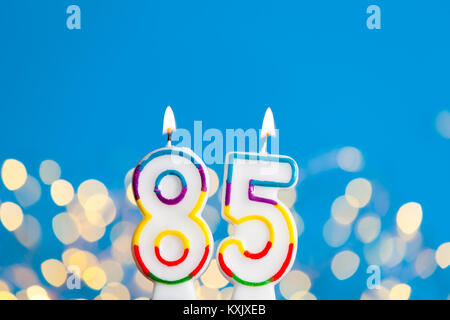 Nummer 85 Geburtstag Kerze gegen einen hellen Lichtern und blauer Hintergrund Stockfoto