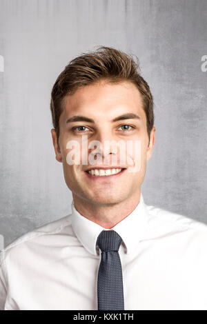 Portrait von lächelnden jungen kaukasischen Geschäftsmann auf konkreten Hintergrund Stockfoto