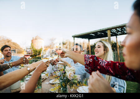 Gruppe von Freunden toasten Weingläser und Spaß im Freien. Die Leute, die Getränke zum Mittagessen im Gartenrestaurant. Stockfoto