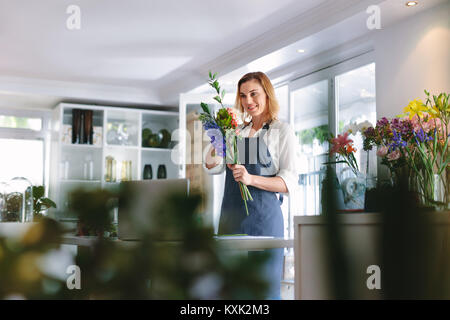 Weibliche florist Schönen Blumenstrauß im Flower Shop. Frau mit Schürze Anordnen von Blumen für die Erstellung von Bouquet. Stockfoto