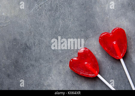 Zwei rote Herzen Form Süßigkeiten Lutscher auf Klebt auf dunklem Stein Hintergrund. Valentine romantische Liebe Grusskarten Banner Poster mit Platz kopieren. Kreative Stockfoto